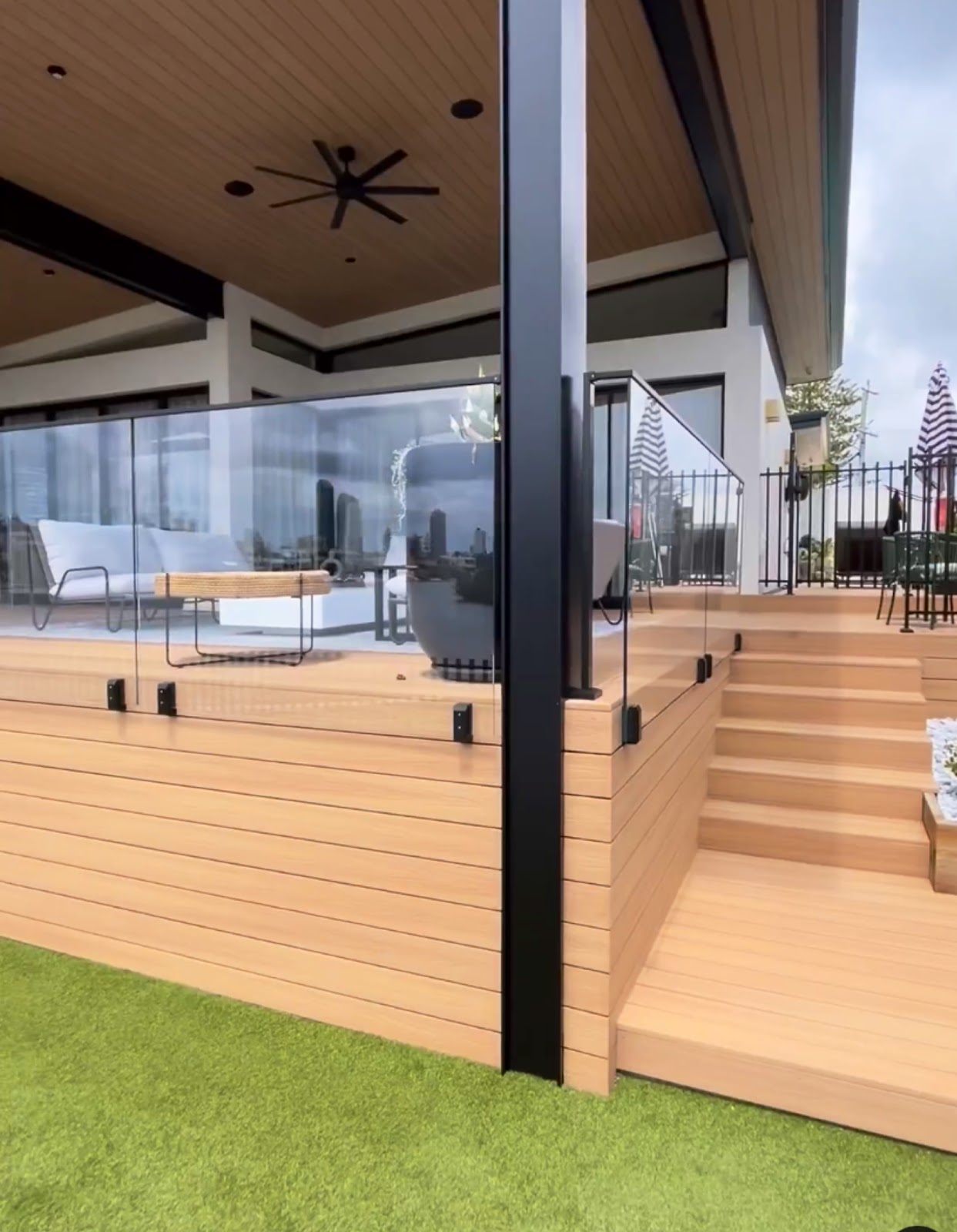 Outdoor living area with timber-look decking, glass balustrade and steps