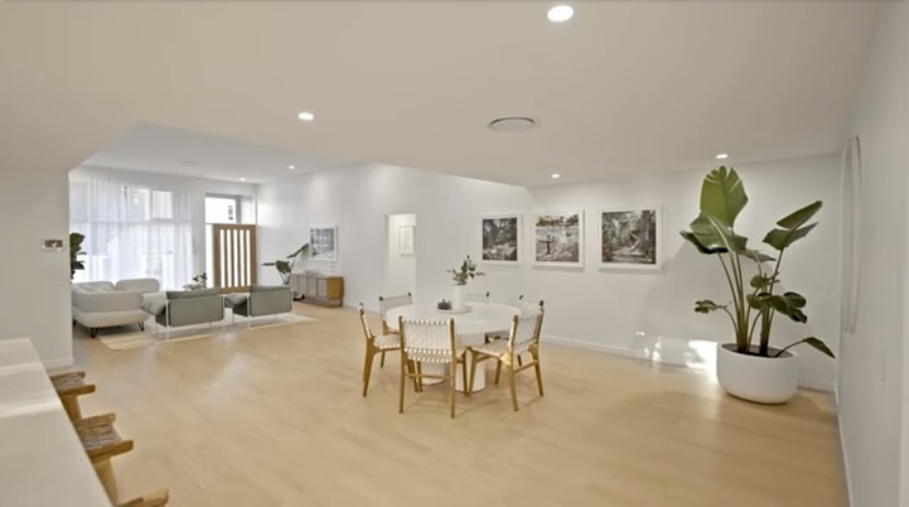 Open plan living and dining area with white walls and timber floors