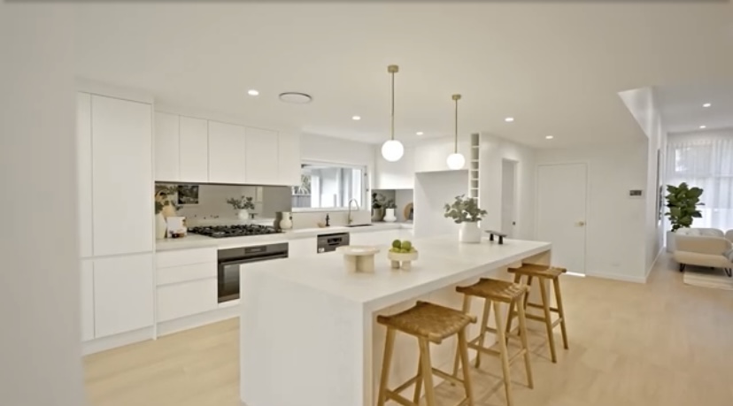 Bright white kitchen with an island bench and timber stools